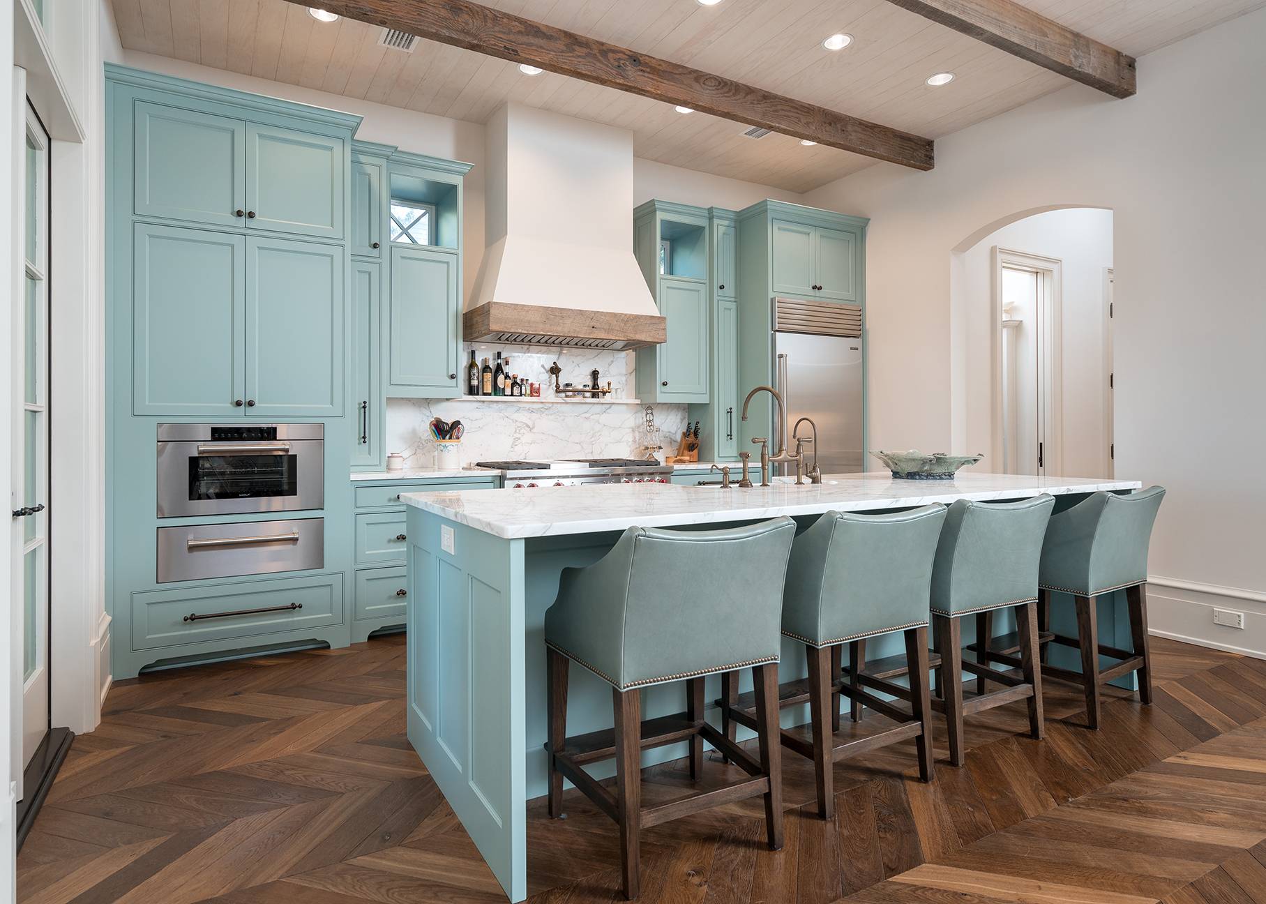 This custom kitchen has inset shaker doors painted a sea blue with specialty window cutouts framing the hood
