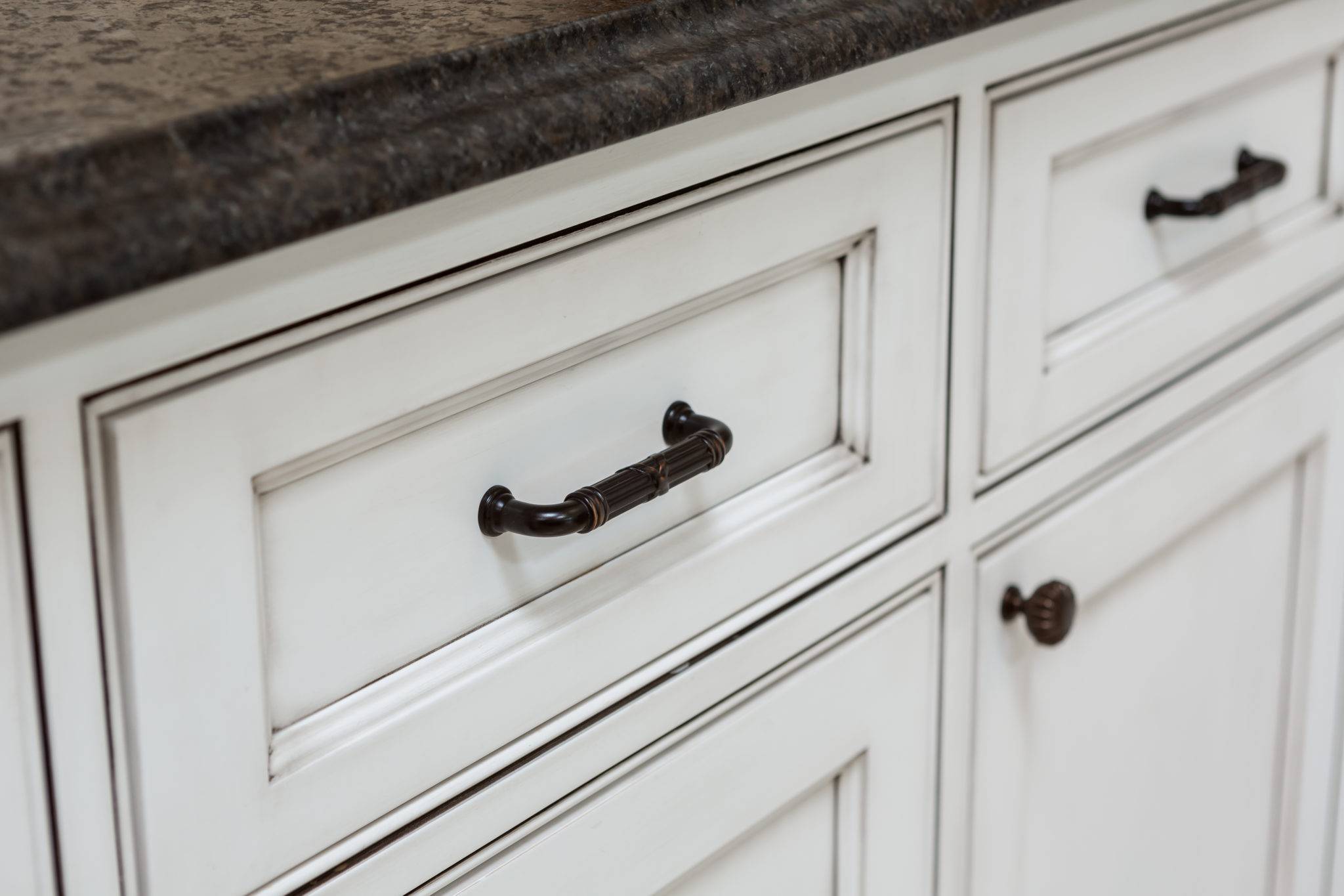 Top Knob pulls on a white painted beaded inset cabinet with recessed panel doors.