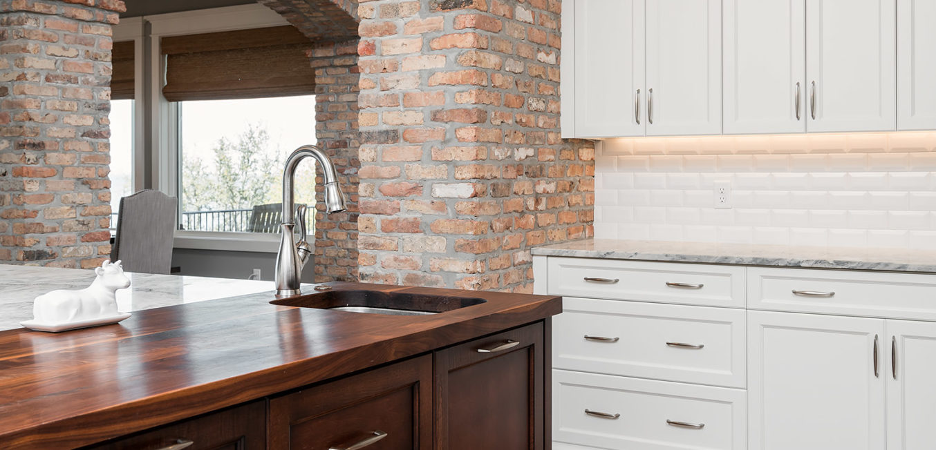 Full Overlay cabinetry with shaker door and drawer fronts. The kitchen island is in a dark stained wood and the side wall cabinets in all white with brick walls.