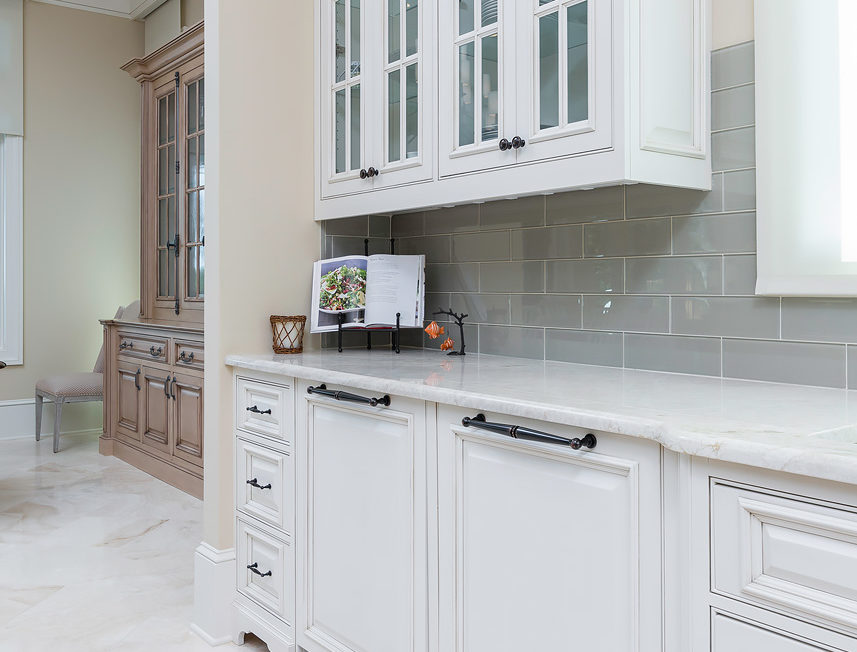 White kitchen cabinets featuring decorative upper mullion frame doors with glass inserts