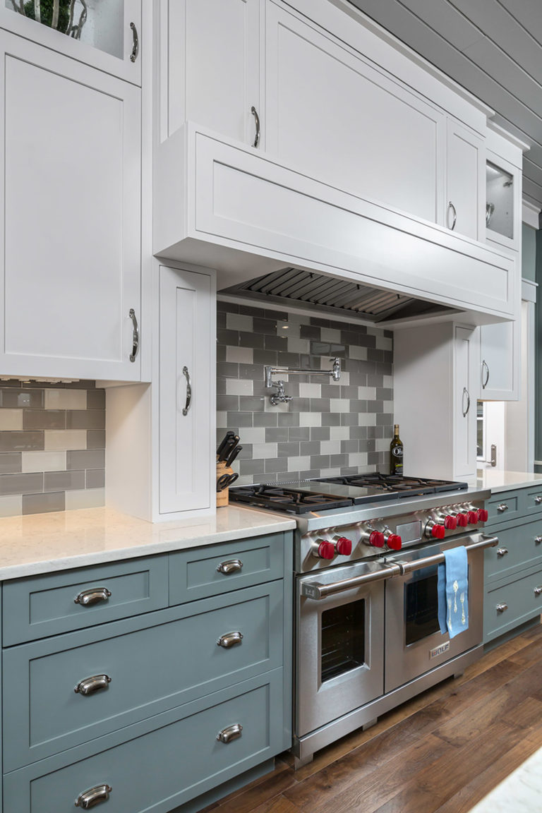 Custom Kitchen featuring inset shaker doors and drawers painted blue and a kitchen island in a barn wood worn finish. Decorative open frame doors on upper cabinets and open shelving for wine bottles.