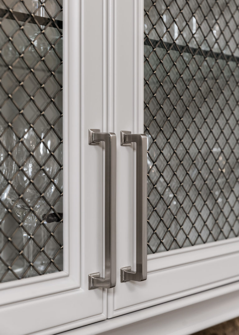 Details on the Top Knobs Ascendra pull in Brushed Satin Nickel on open framed doors with glass panels and decorative metal meshing overlay
